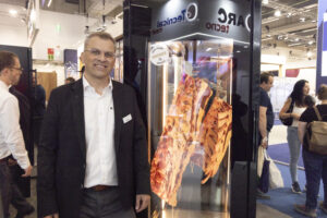 Thomas Ott, Head of Sales; Business Development bei der Landig Group, am Stand mit dem Original: dem Dry Ager. Die mehrfach ausgezeichneten Reifeschränke made in Germany begeisterten auf der IFFA 2025 mit der innovativen Smart-Aging®-Technologie – für die präzise Reifung von Fleisch, Wurst, Schinken, Fisch, Käse und Geflügel. „Unsere Lösungen verbinden Handwerk und Hightech – und machen Dry Aging einfacher, sicherer und vielseitiger als je zuvor.“ Mit jahrzehntelanger Erfahrung und einem globalen Vertriebsnetz bleibt Dry Ager die Nummer eins für professionelle Reifetechnologie. © Matthias Wenger